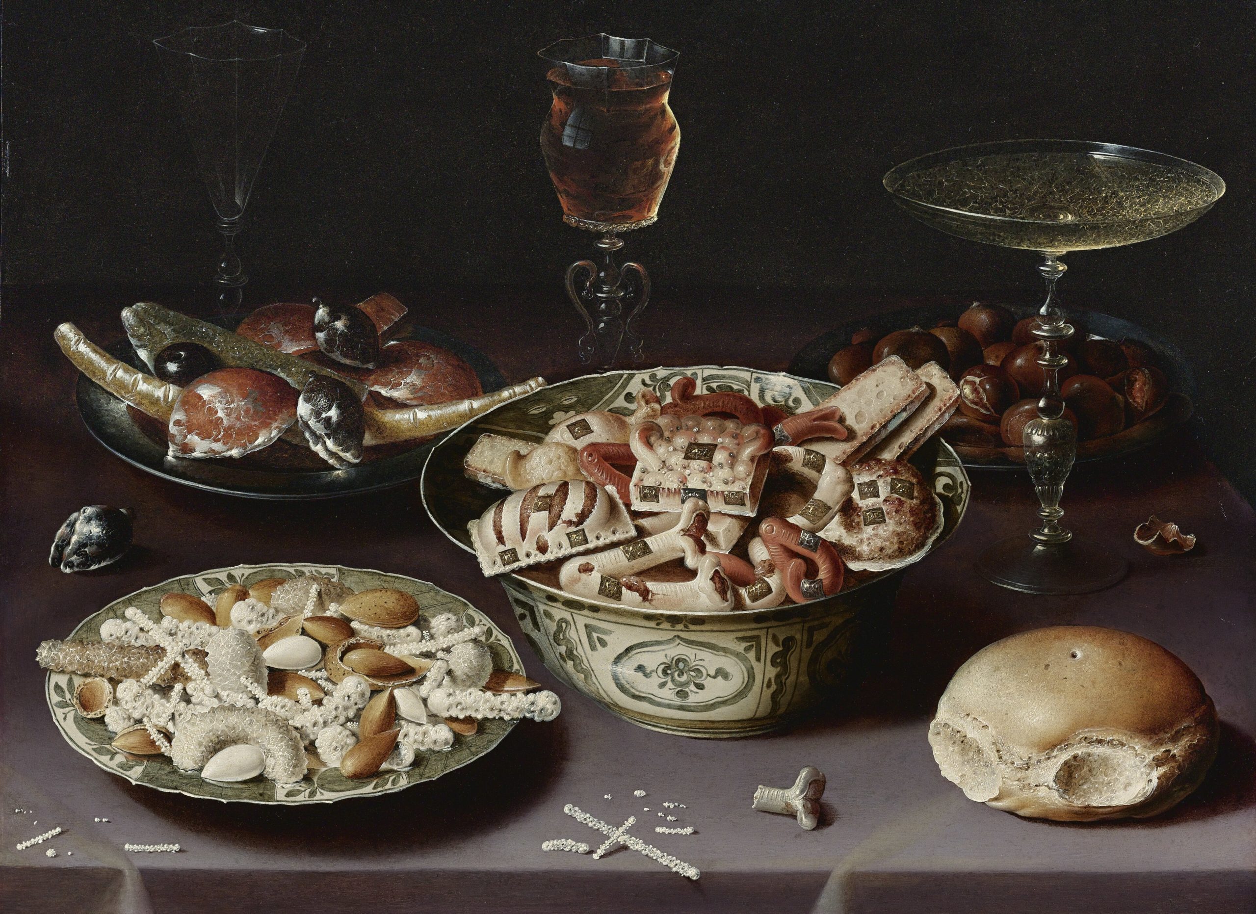 Osias Beert Still life of porcelain vessels containing sweets pewter plates bearing sweets and chestnuts three pieces of glassware and a bread roll on a table draped with a mauve cloth scaled
